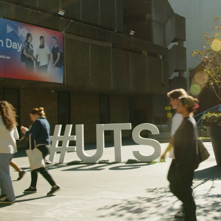 Students walking into UTS tower building. A #UTS sign and UTS Open Day banner in the background.