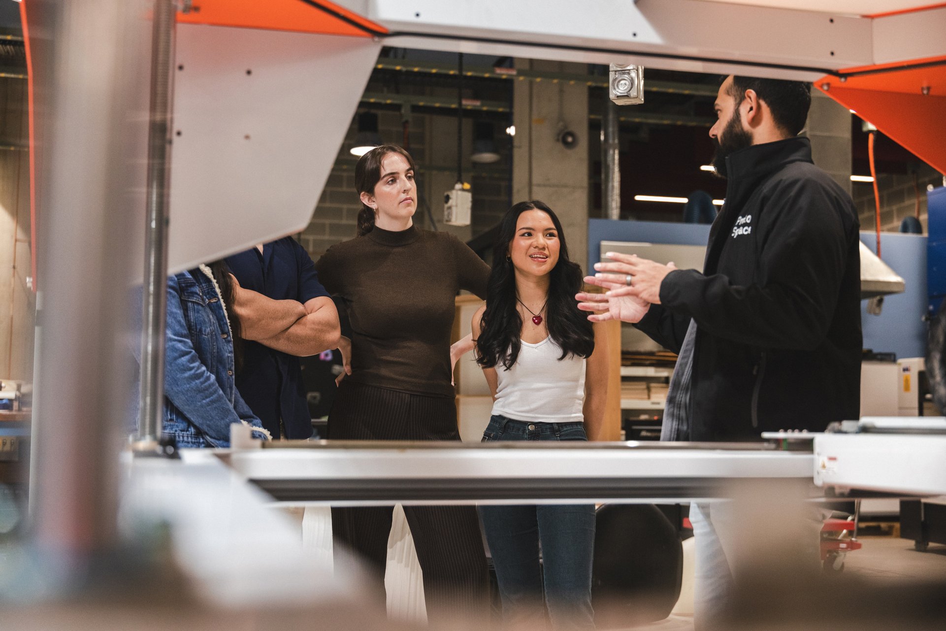 University of Technology Sydney Protospace staff member talking to students in front of one of the 3D printing machines.
