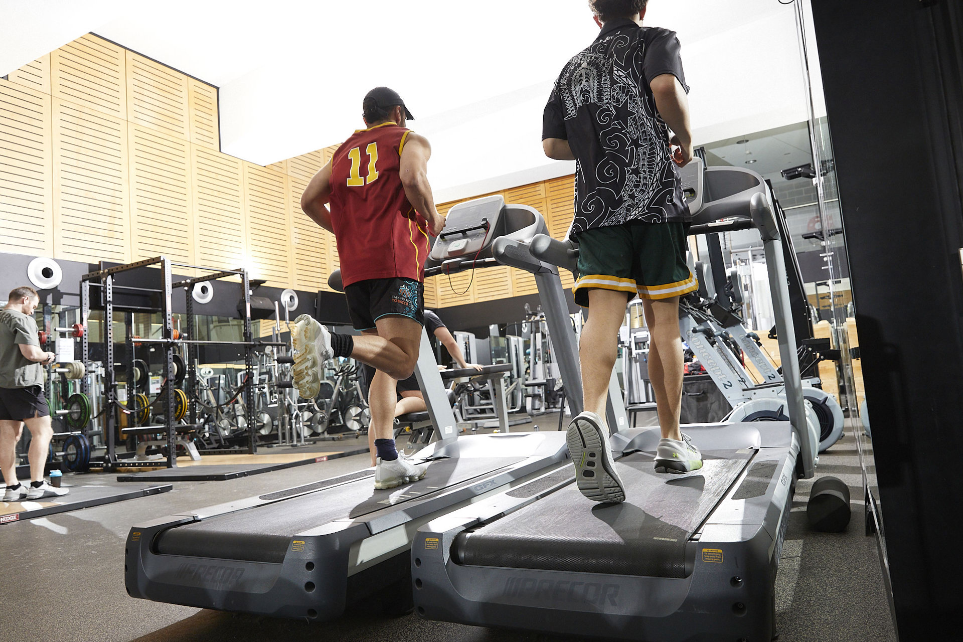 Two men running on treadmills in a gym, focused on their workout and maintaining a healthy lifestyle.