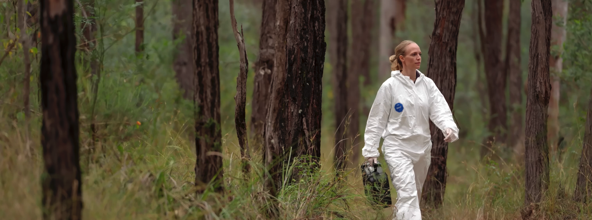 Dr Maiken carries a briefcase through the bush